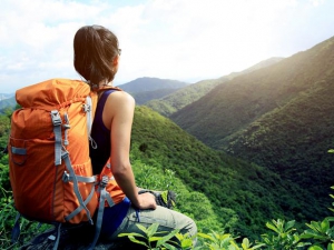 Young woman pausing while backpacking in rolling hills