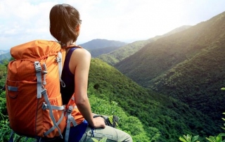 Young woman pausing while backpacking in rolling hills