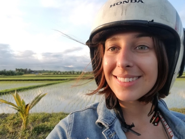 A selfie photo by Arletta Gromek wearing a scooter helmet, in front of a landscape in Indonesia