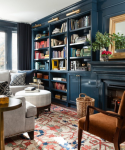 Photo of a blue-green room with wall-spanning bookshelves and white and brown sitting room furniture